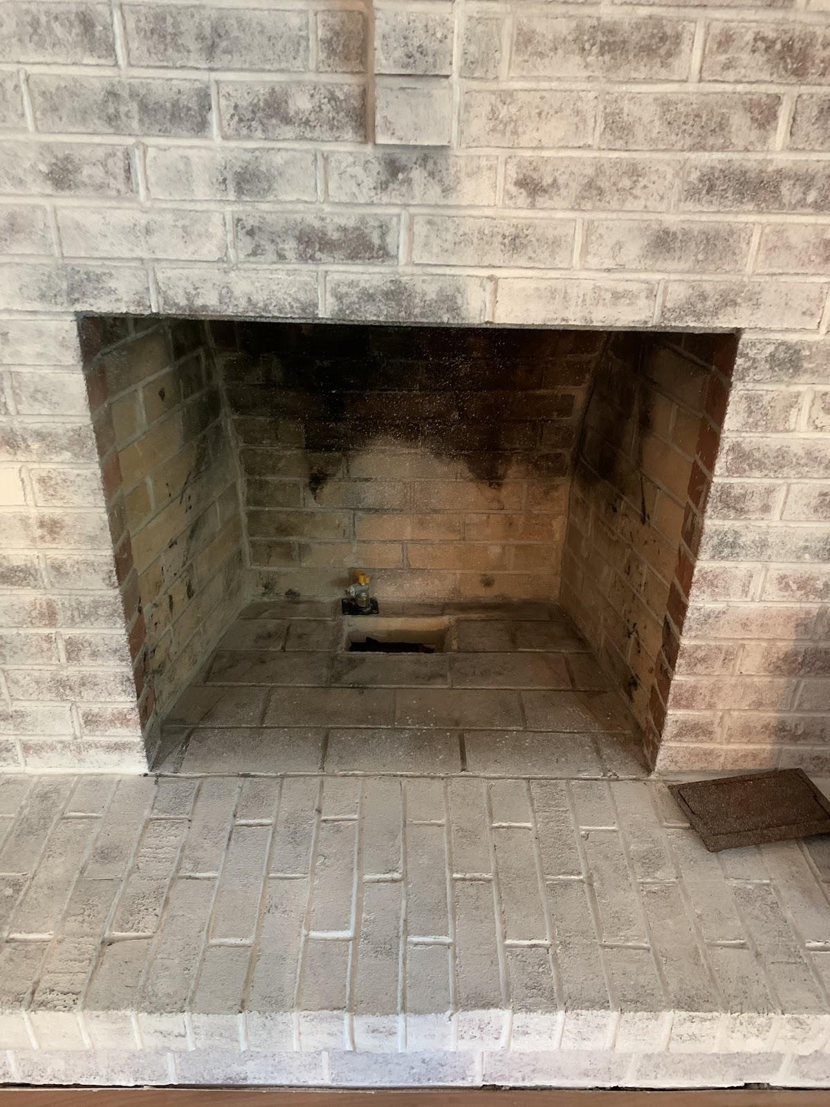 Gas line installed inside a whitewashed brick fireplace