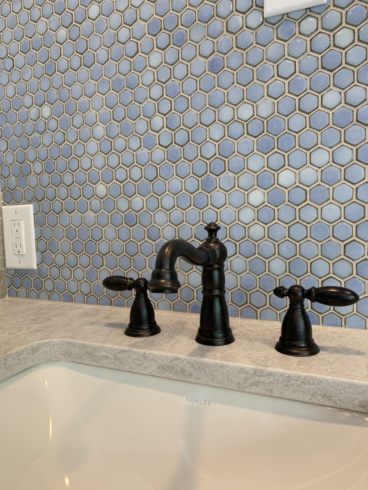 Bronze faucet detail against a blue penny tile feature wall